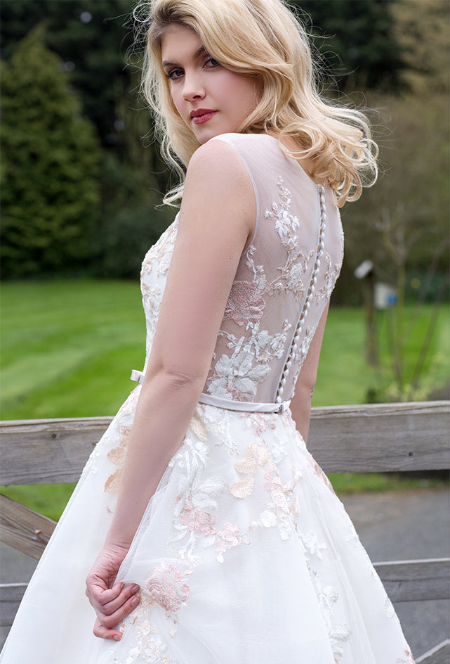 Closeup of back of tulle tea length wedding dress with floral appliques throughout bodice and skirt