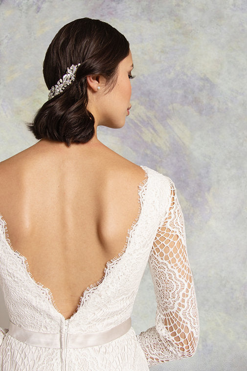 Close up of lace fishtail wedding dress with long sleeves with a  soft satin belt on waistline and deep plunging neckline mirrored with a matching deep V- back