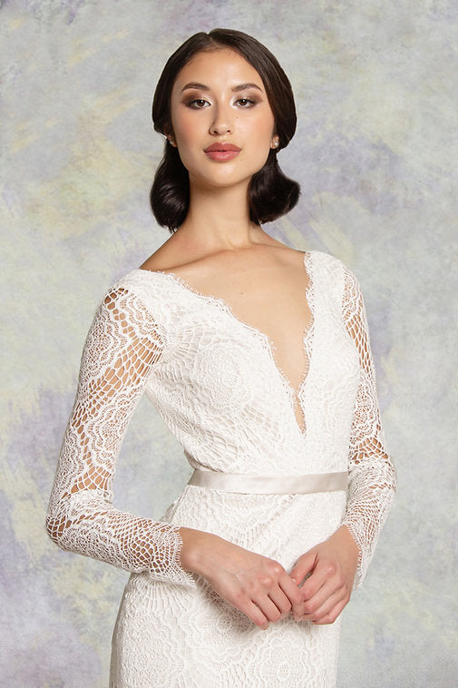 The bodice of the lace fishtail wedding dress with long sleeves with a  soft satin belt on waistline and deep plunging neckline mirrored with a matching deep V- back
