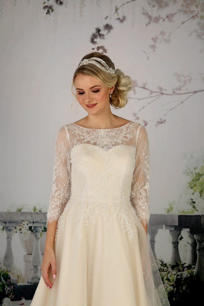 Close up of the Cora tea length wedding dress'  lace in champagne