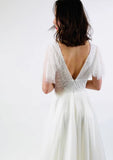 Back of full length wedding dress with a sheer sequined bodice, layered sleeves and full tulle skirt.