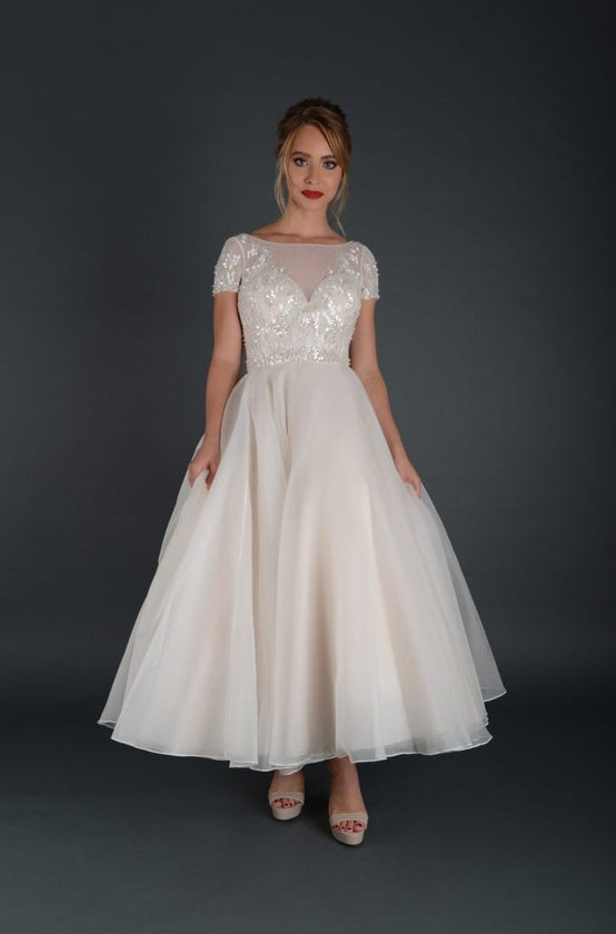 Tea length bridal gown with embellished bodice and cap sleeve.