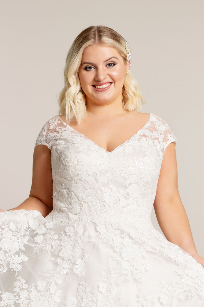 Close up of tea length wedding dress in luxury lace and with a deep v neck bodice cut especially for curvy girls.